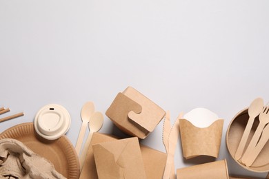 Photo of Eco friendly food packaging. Paper containers and tableware on light grey background, flat lay. Space for text