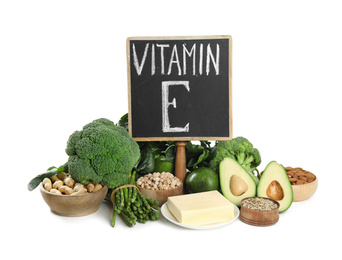 Small chalkboard with phrase Vitamin E and different products on white background