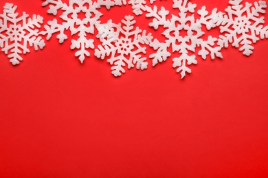 Photo of Beautiful decorative snowflakes on red background, flat lay. Space for text