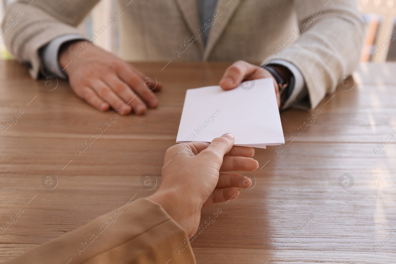 Photo of Employee giving resignation letter to boss in office, closeup