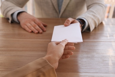 Photo of Employee giving resignation letter to boss in office, closeup