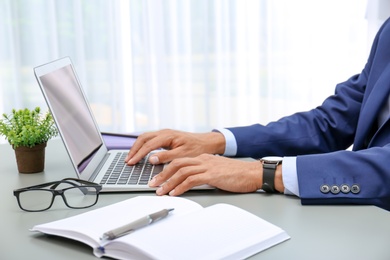 Man in office wear using laptop at table indoors