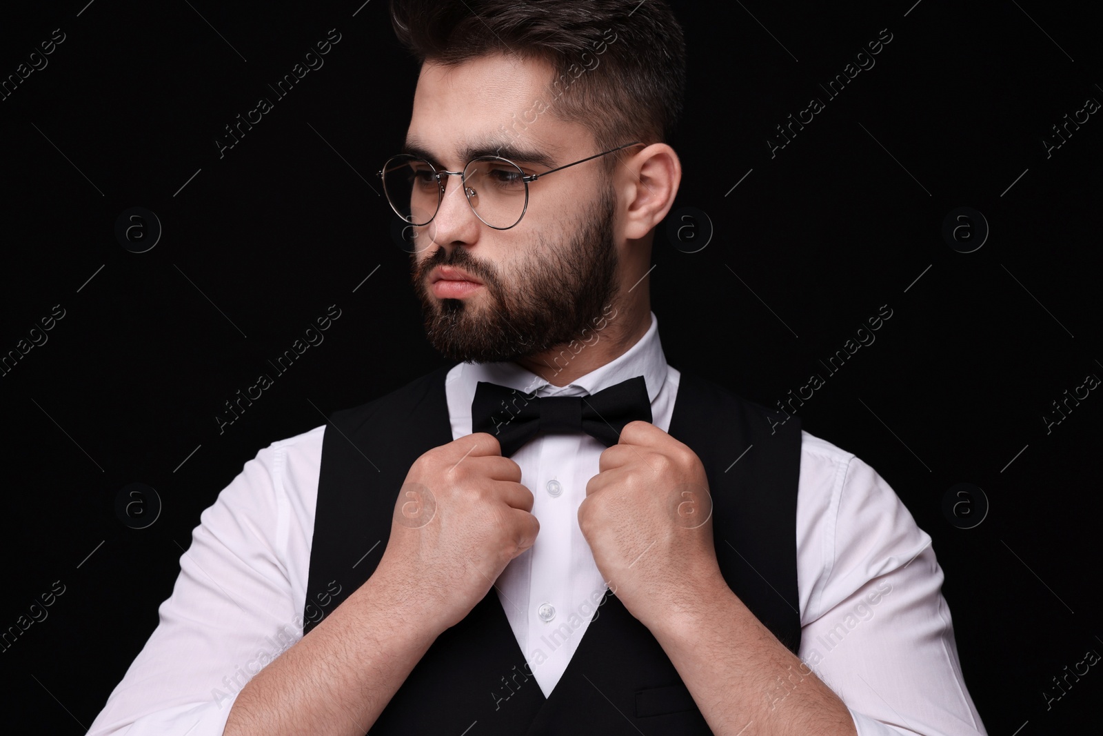 Photo of Portrait of handsome man in shirt and bow tie on black background