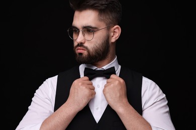 Portrait of handsome man in shirt and bow tie on black background