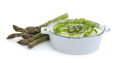 Delicious asparagus soup with arugula isolated on white