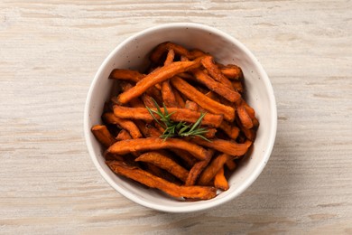 Photo of Bowl with sweet potato fries and rosemary on wooden table, top view