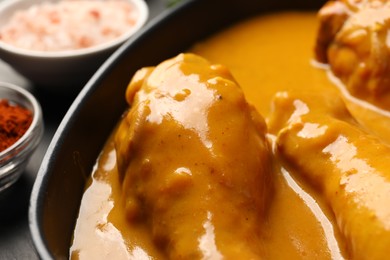 Tasty chicken curry and ingredients on black table, closeup