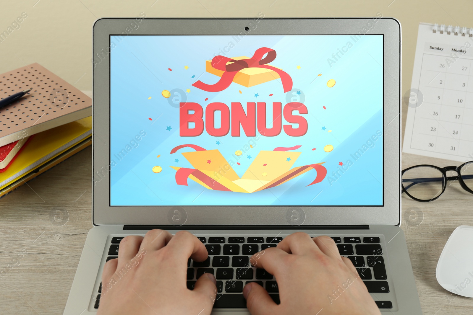 Image of Bonus gaining. Woman using laptop at wooden table, closeup. Illustration of open gift box, word and confetti on device screen