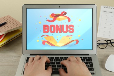 Bonus gaining. Woman using laptop at wooden table, closeup. Illustration of open gift box, word and confetti on device screen