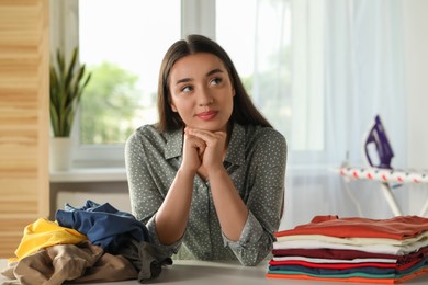 Young woman at table with different clothes indoors