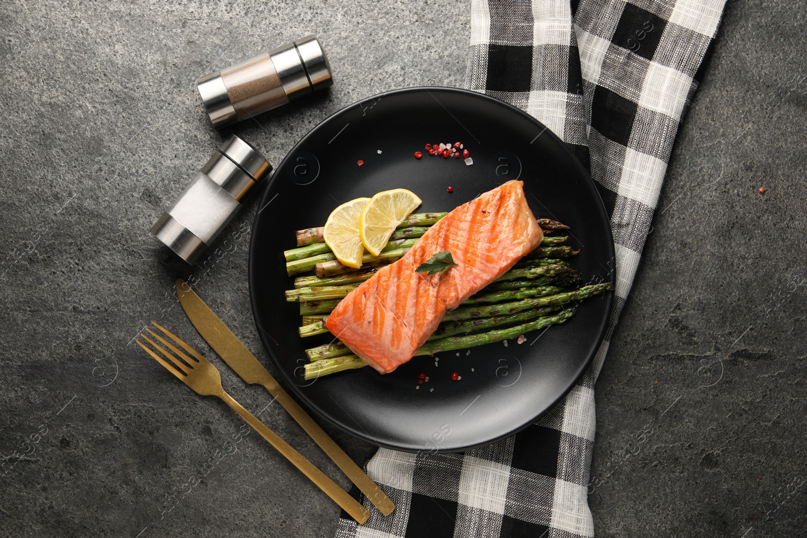 Photo of Tasty grilled salmon with asparagus, lemon and spices served on gray table, flat lay