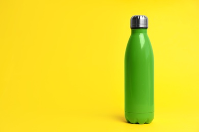 Photo of Stylish thermo bottle on yellow background, space for text