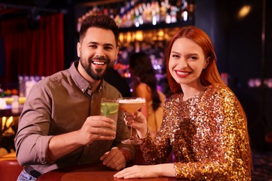 Happy couple clinking glasses with fresh cocktails at table in bar