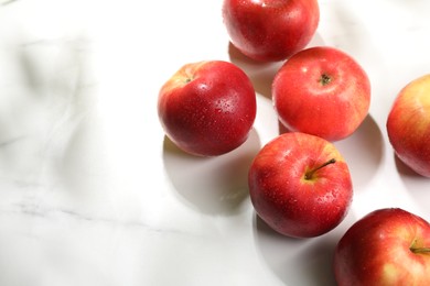 Photo of Fresh red apples with water drops on white marble table, flat lay. Space for text