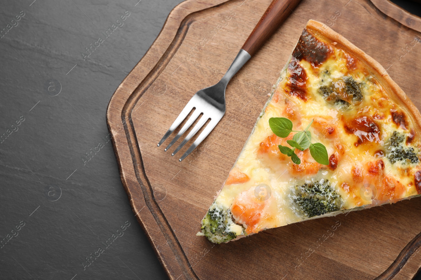 Photo of Piece of delicious homemade salmon quiche with broccoli and fork on black table, top view. Space for text