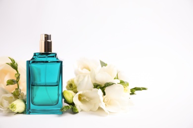Photo of Bottle of perfume and beautiful flowers on white background
