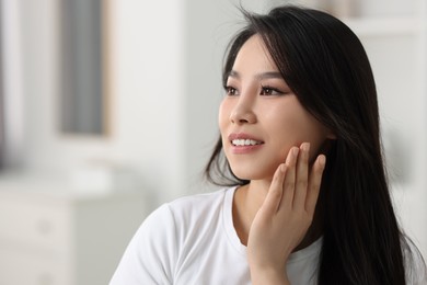 Portrait of beautiful woman with perfect skin at home, space for text