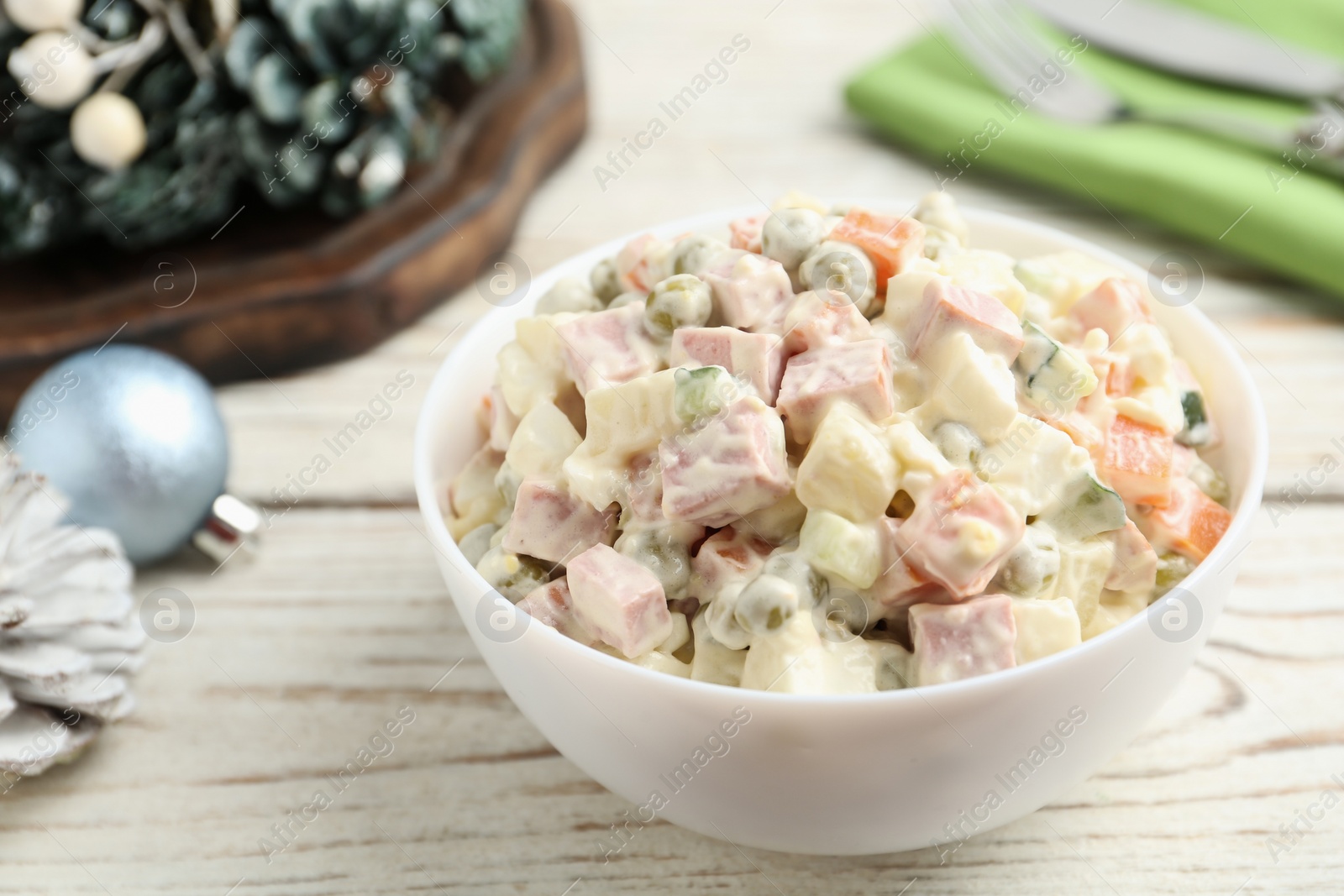 Photo of Traditional russian salad Olivier served on white wooden table