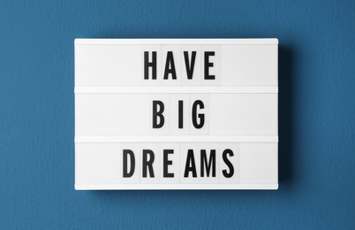 Photo of Lightbox with motivational quote Have Big Dreams on blue background, top view
