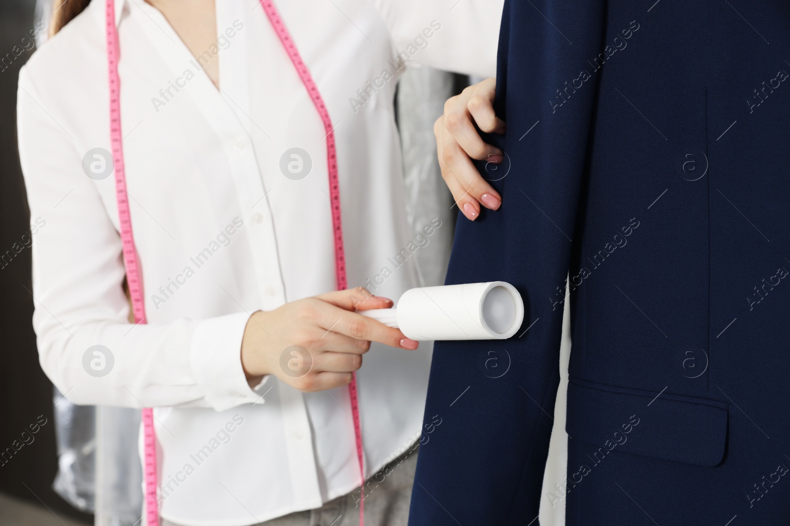 Photo of Woman using adhesive lint roller indoors, closeup. Dry-cleaning service