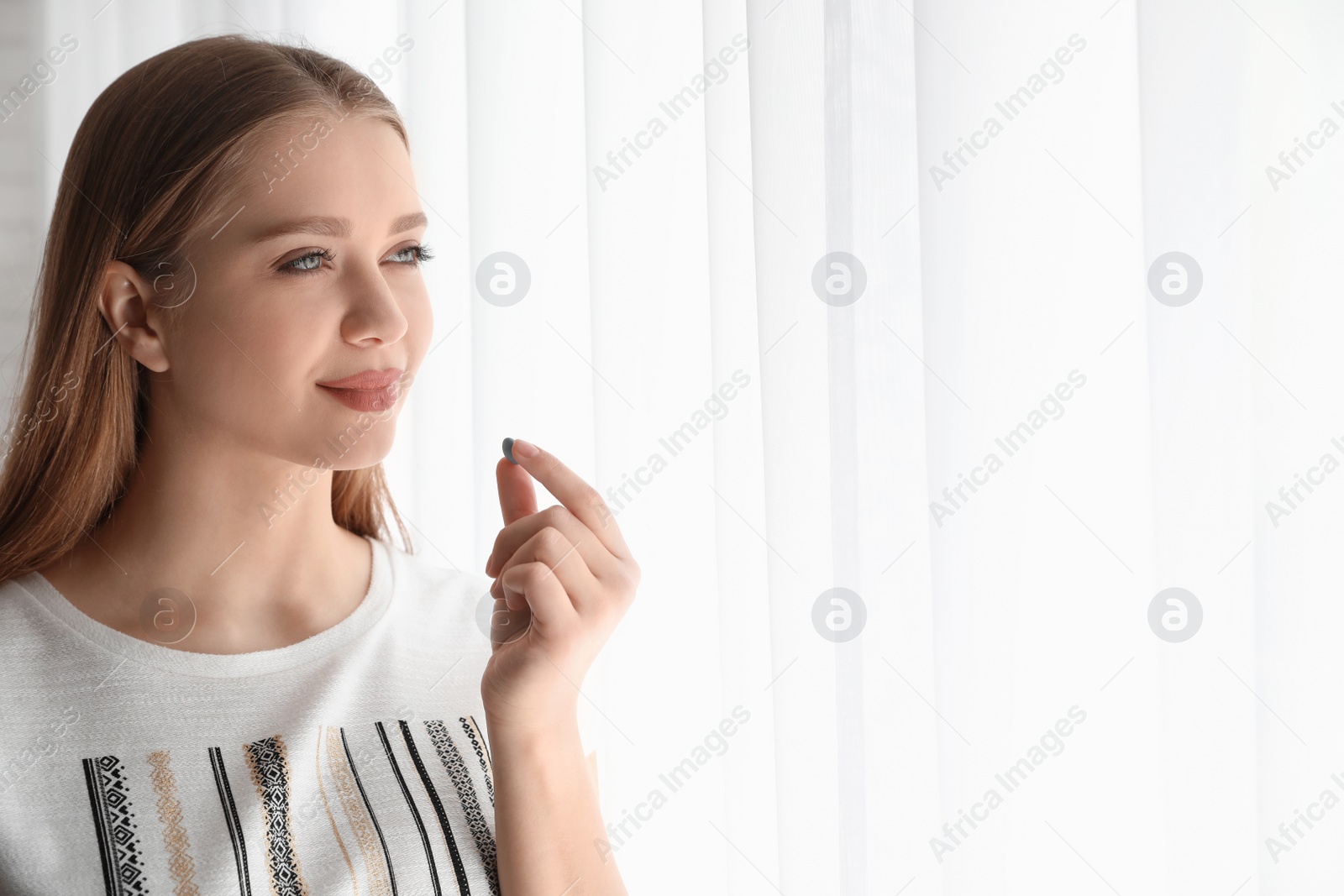 Photo of Young woman with vitamin pill indoors. Space for text