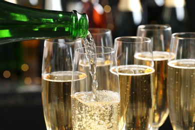 Photo of Pouring champagne into glasses on blurred background, closeup