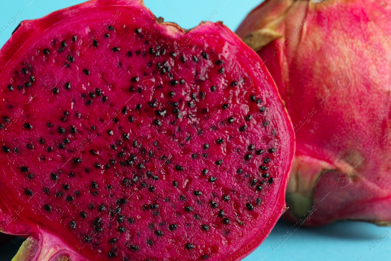 Photo of Delicious cut red pitahaya fruit on light blue background, closeup