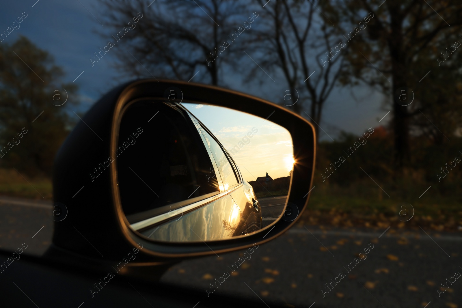 Photo of Side view mirror of car outdoors at sunset, closeup