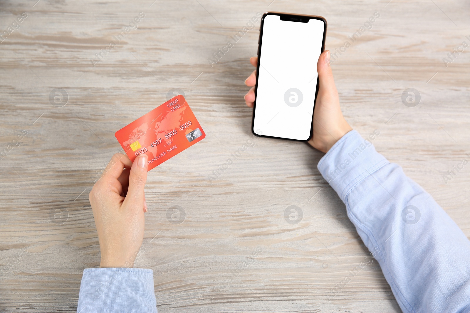 Photo of Online payment. Woman using credit card and smartphone with blank screen at light wooden table, top view