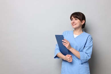 Photo of Portrait of smiling medical assistant with clipboard on grey background. Space for text