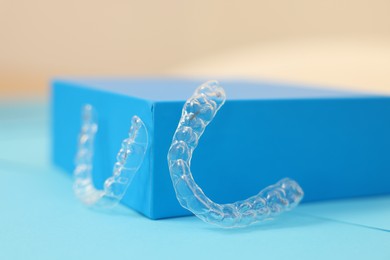 Photo of Transparent dental aligners on color background, closeup