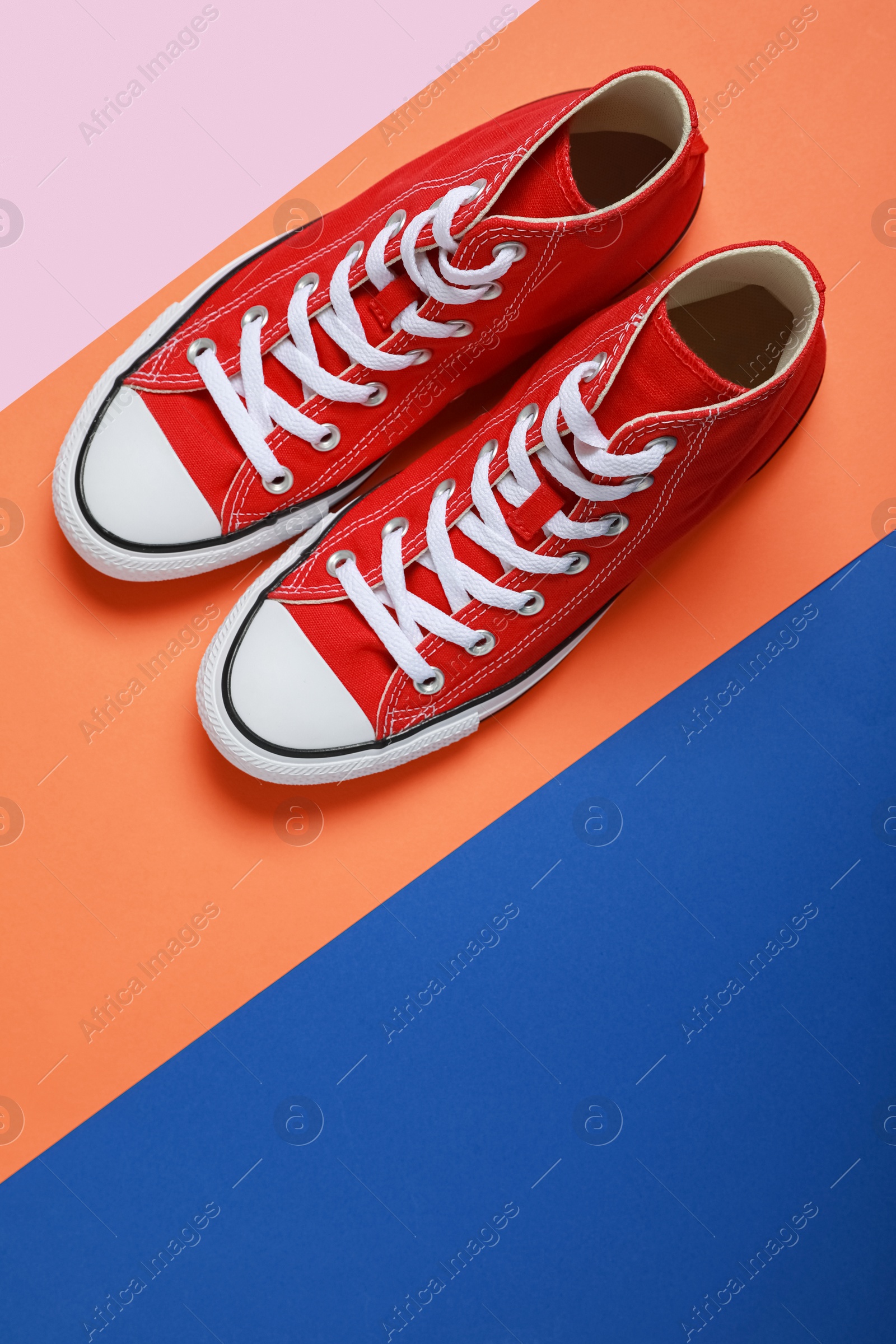 Photo of Pair of new stylish red sneakers on colorful background, flat lay. Space for text