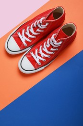 Photo of Pair of new stylish red sneakers on colorful background, flat lay. Space for text