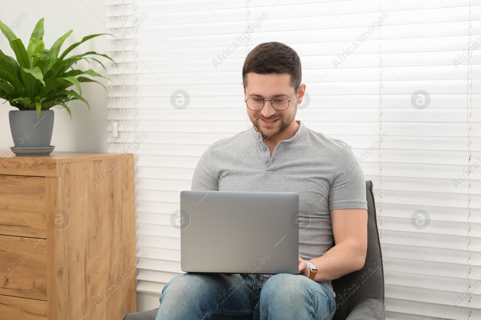 Photo of Man working with laptop in armchair at home