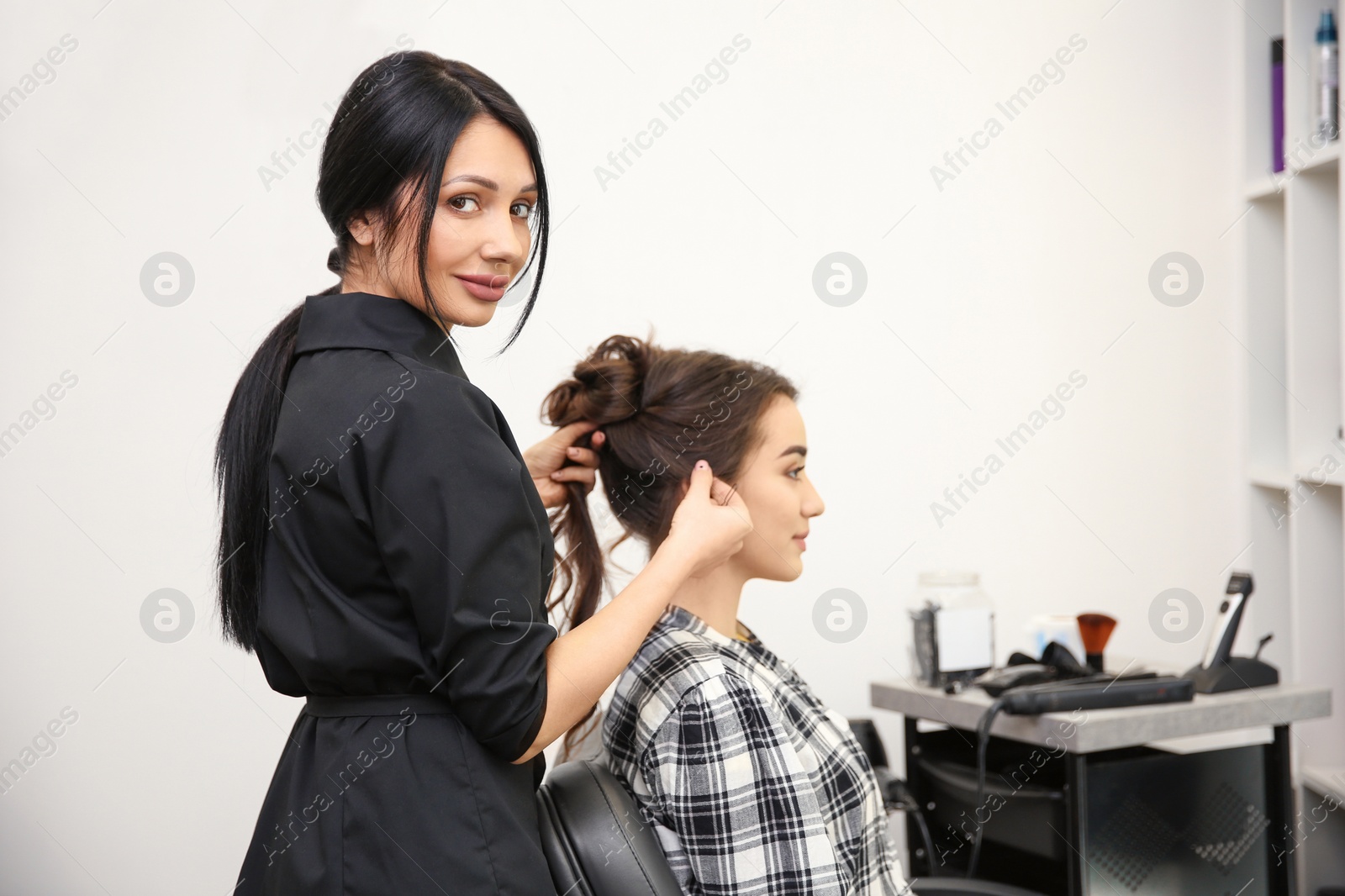 Photo of Professional female hairdresser working with client in salon