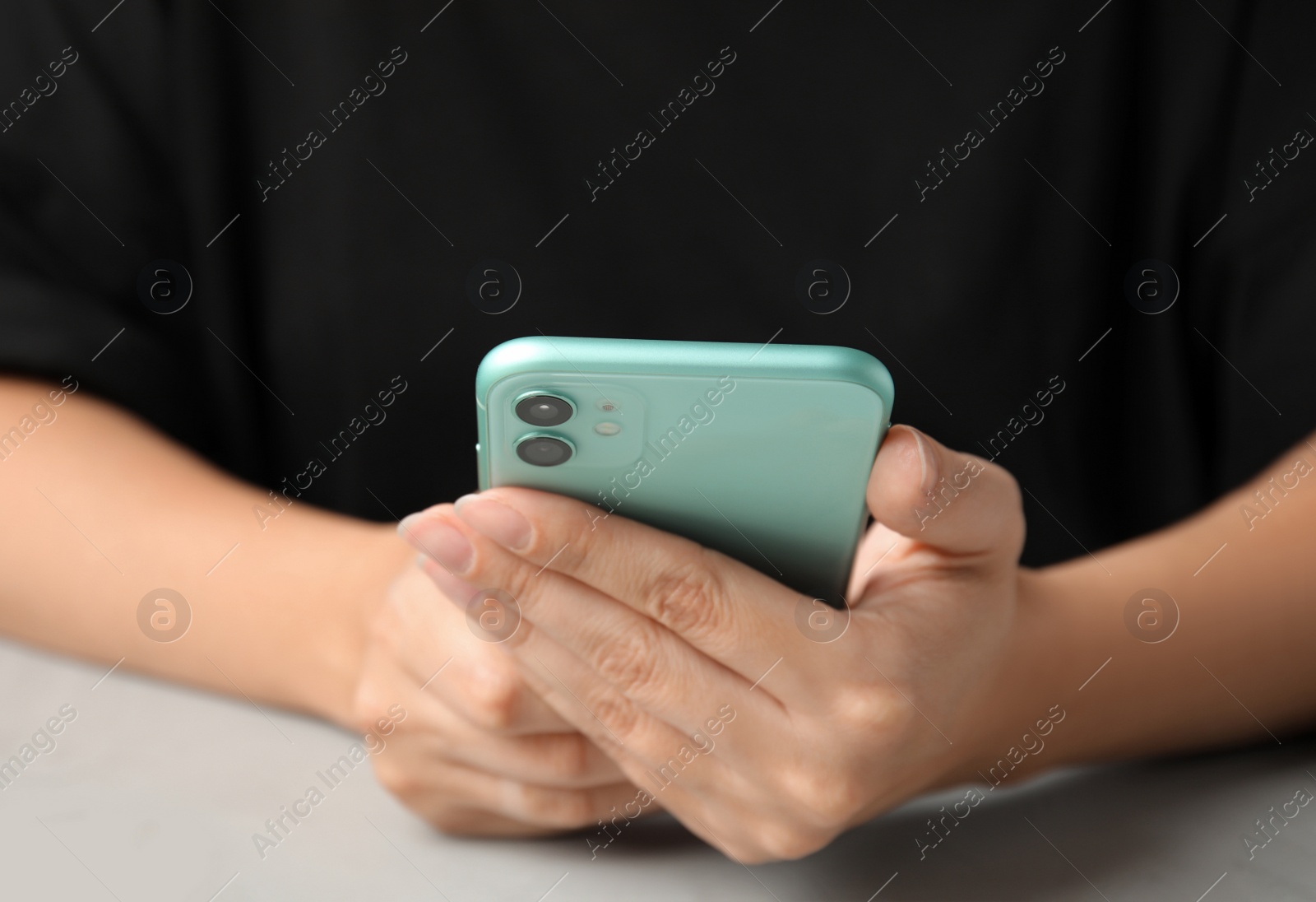 Photo of MYKOLAIV, UKRAINE - JULY 9, 2020: Woman holding Iphone 11 Green at table, closeup