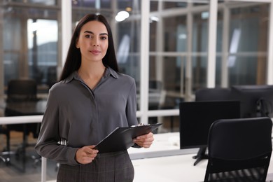 Photo of Beautiful woman with clipboard in office, space for text. Lawyer, businesswoman, accountant or manager