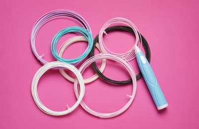 Stylish 3D pen and colorful plastic filaments on pink background, flat lay