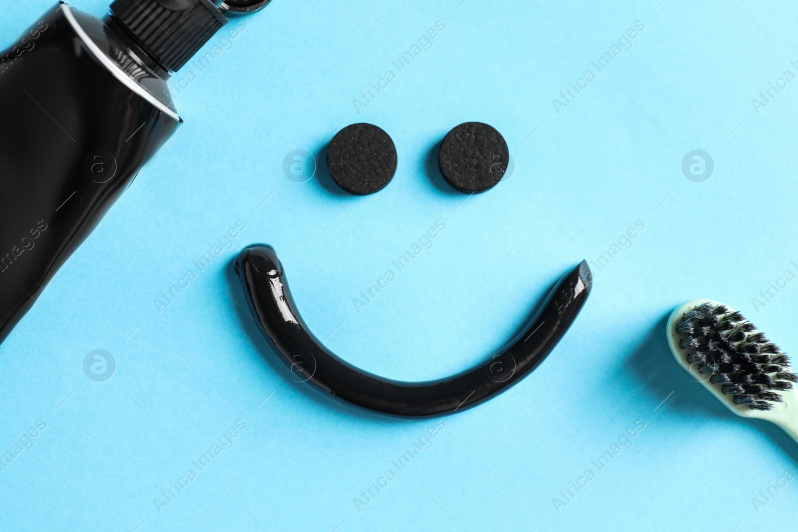 Photo of Flat lay composition with charcoal toothpaste on light blue background