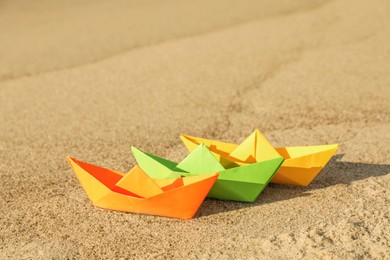 Photo of Bright color paper boats on sandy beach near sea