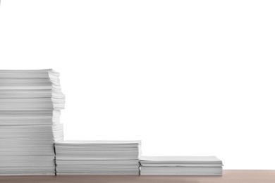 Photo of Stacks of paper sheets on wooden table against white background