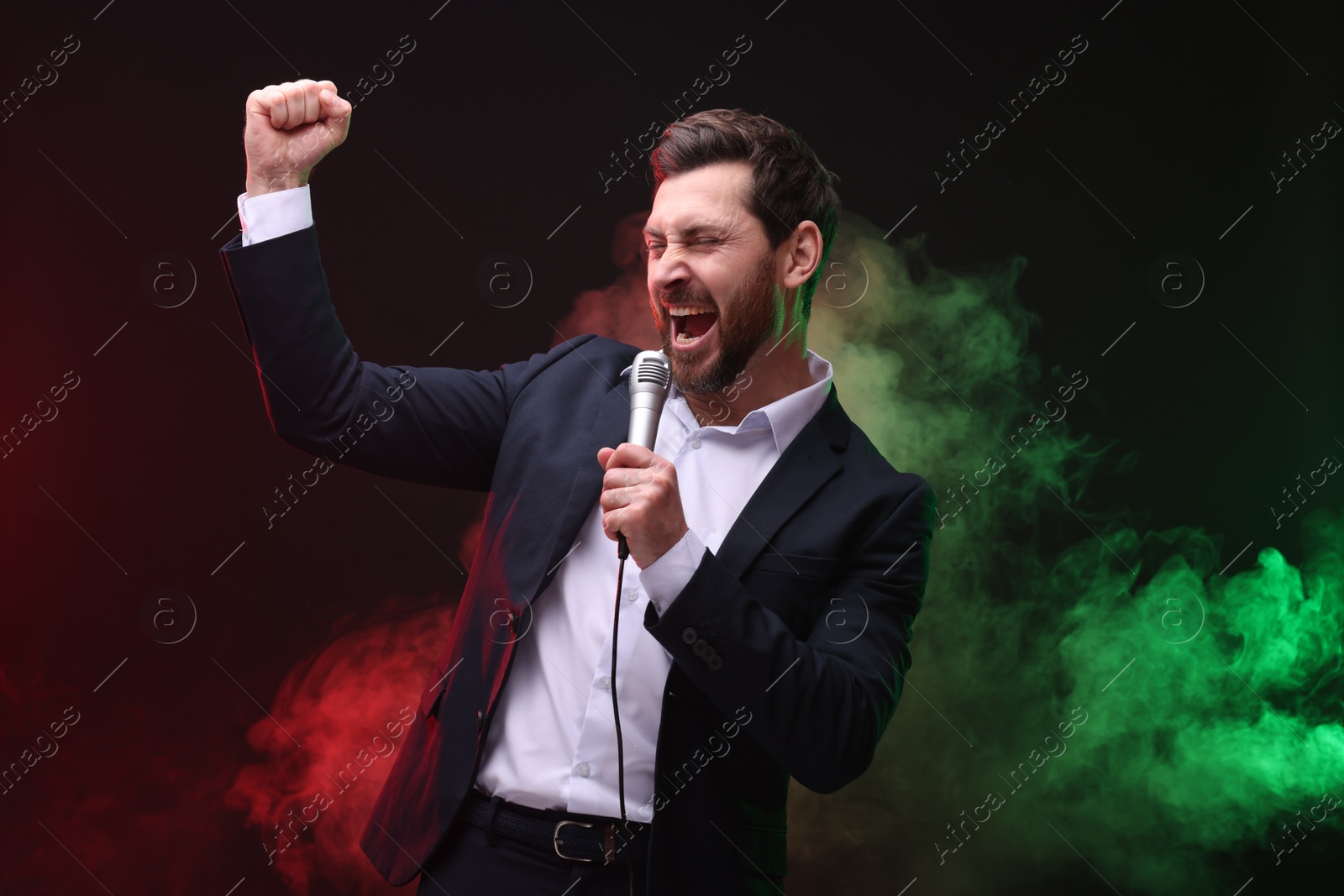 Photo of Emotional man with microphone singing in color lights