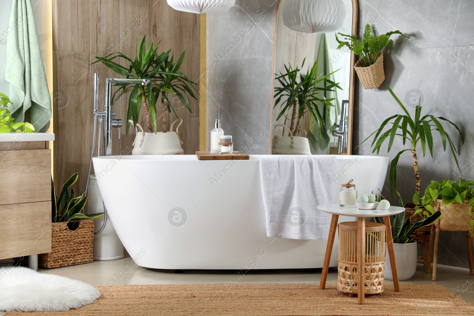 Photo of Modern white tub and beautiful green houseplants in bathroom. Interior design