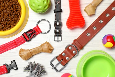 Photo of Flat lay composition with dog collars, toys and food on white wooden table