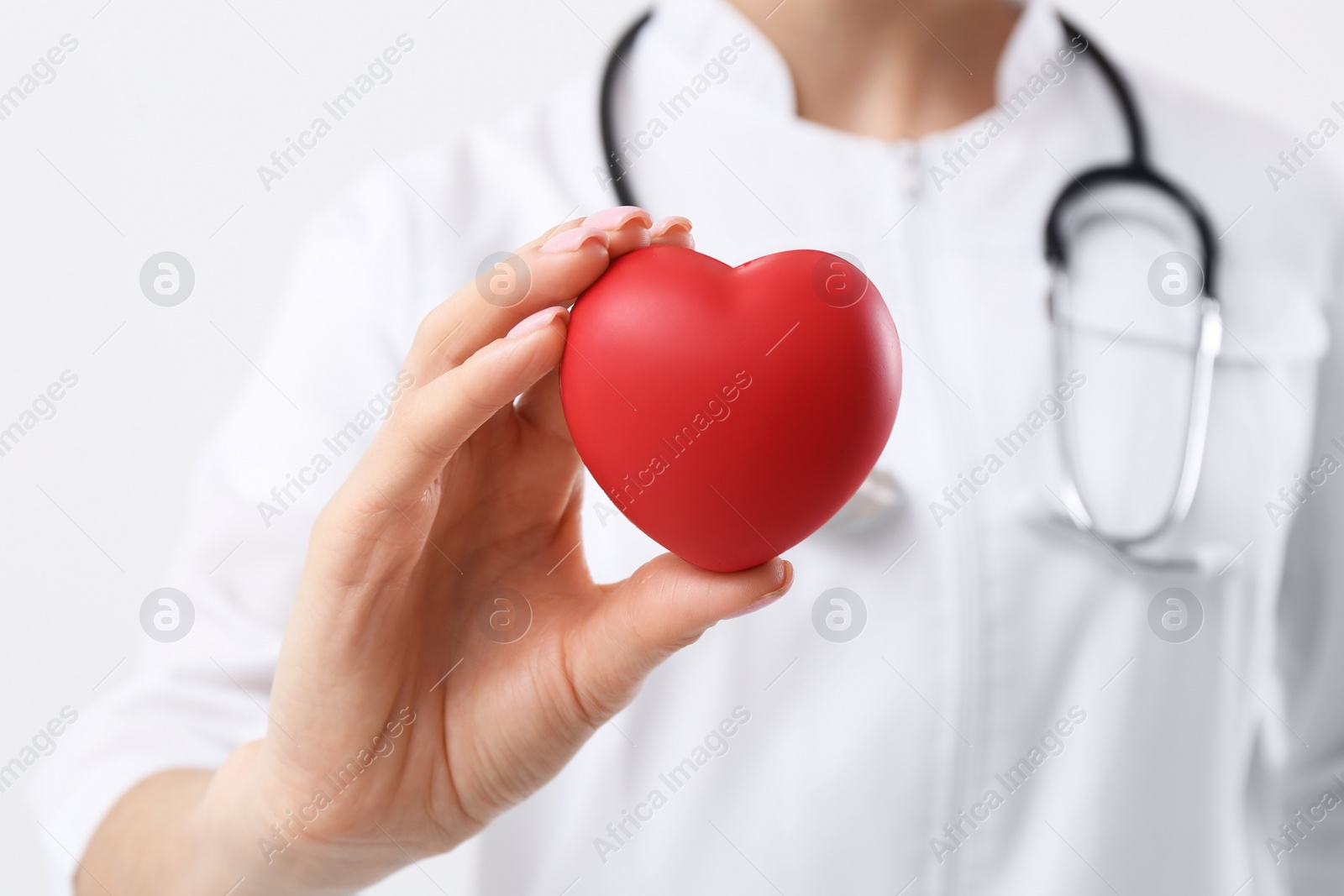 Photo of Doctor holding red heart on white background, closeup. Cardiology concept