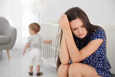 Photo of Young mother suffering from postnatal depression and little baby in room