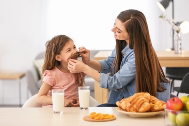 Photo of Mother and daughter playing while having breakfast with milk at table