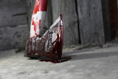 Axe with blood on floor indoors, closeup. Space for text