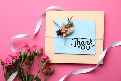Photo of Card with phrase Thank You and beautiful flowers on pink background, flat lay