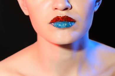 Photo of Beautiful young model with creative lips makeup on black background